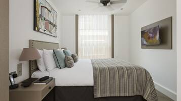 A neatly arranged hotel room with a bed, bedside table, lamp, and artwork on the walls.