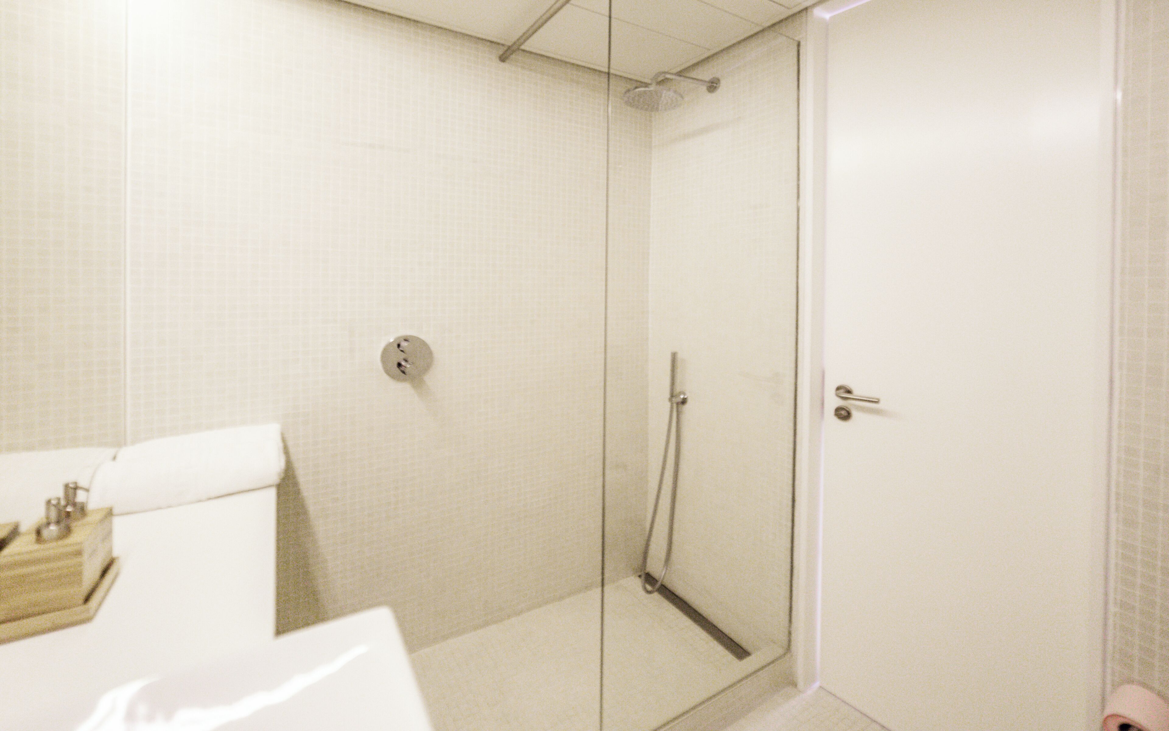 Een badkamer met een douchecabine van glas, een wit toilet en een wastafel met spiegel.