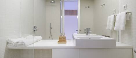 A modern bathroom with a large mirror, two sinks, and a shower.