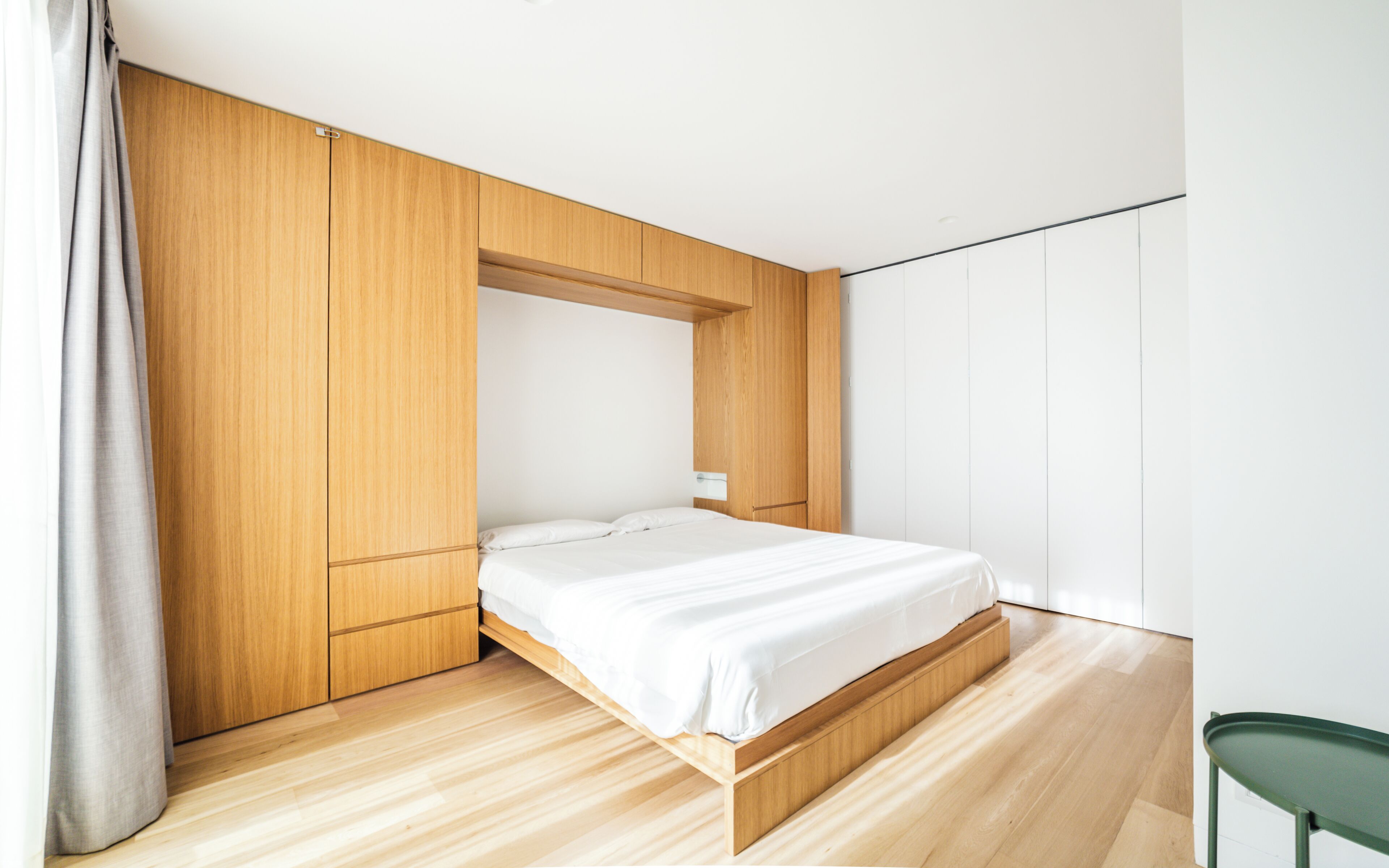 A modern bedroom with a wooden bed frame, a built-in bench, and a minimalist design.