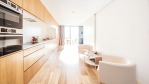 A modern kitchen with Bosch appliances, wooden cabinets, and a dining area with a white sofa and table. - Edmond Vibes Barrio de Salamanca (Madrid)