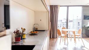 A modern kitchen with a sink, a fruit bowl, and a dining area with a table and chairs. - Edmond Vibes Barrio de Salamanca (Madrid)