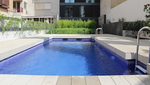 A rectangular swimming pool with a tiled edge, surrounded by a wooden deck and a metal ladder. - Edmond Vibes Barrio de Salamanca (Madrid)