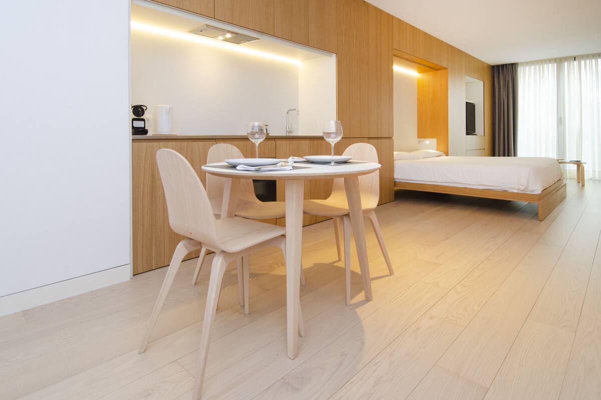 Una habitación de hotel moderna con comedor, cama y baño.