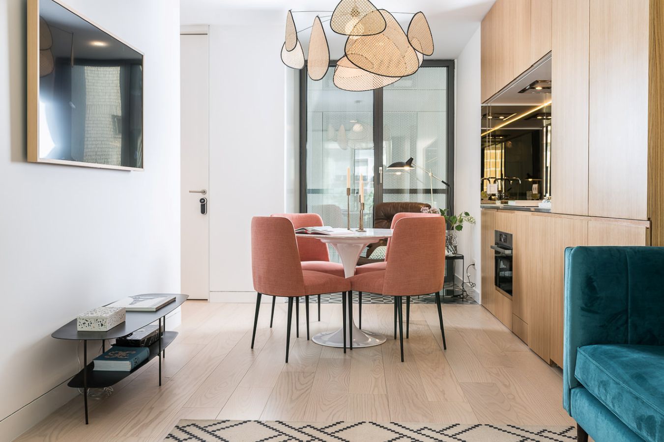 Une cuisine moderne avec des meubles en bois, un coin repas avec des chaises roses et un canapé turquoise.