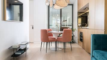 Une cuisine moderne avec des meubles en bois, un coin repas avec des chaises roses et un canapé turquoise.