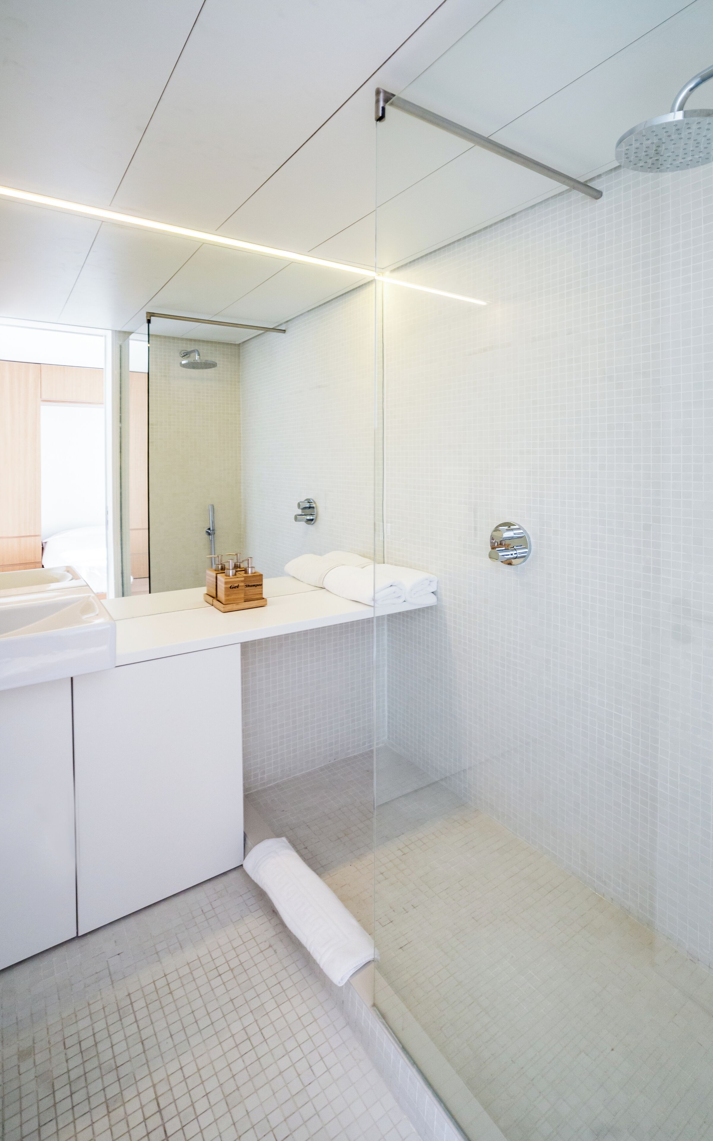 Un baño moderno con cabina de ducha de vidrio, un lavabo blanco y un espejo.