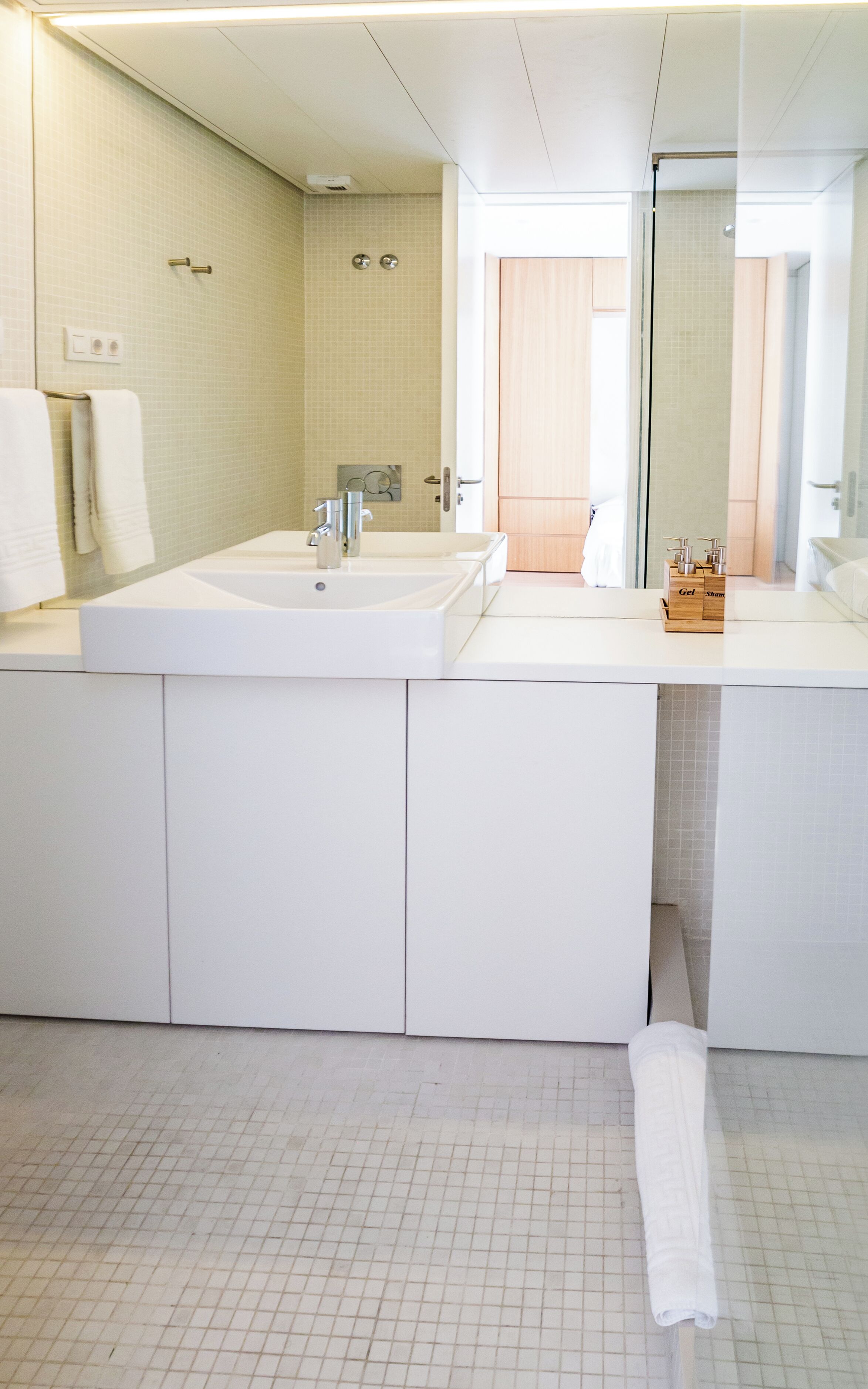 A modern bathroom with a large mirror, two sinks, and a shower area.
