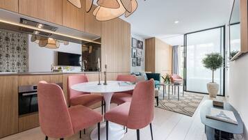 Una cocina moderna con armarios de madera, un comedor con sillas rosa y un ventanal con vistas.