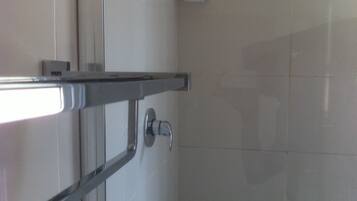Un baño con cabina de ducha de vidrio, una puerta blanca y un perchero para toallas.