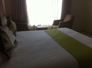 Una habitación de hotel con una cama grande, una silla y una mesita.