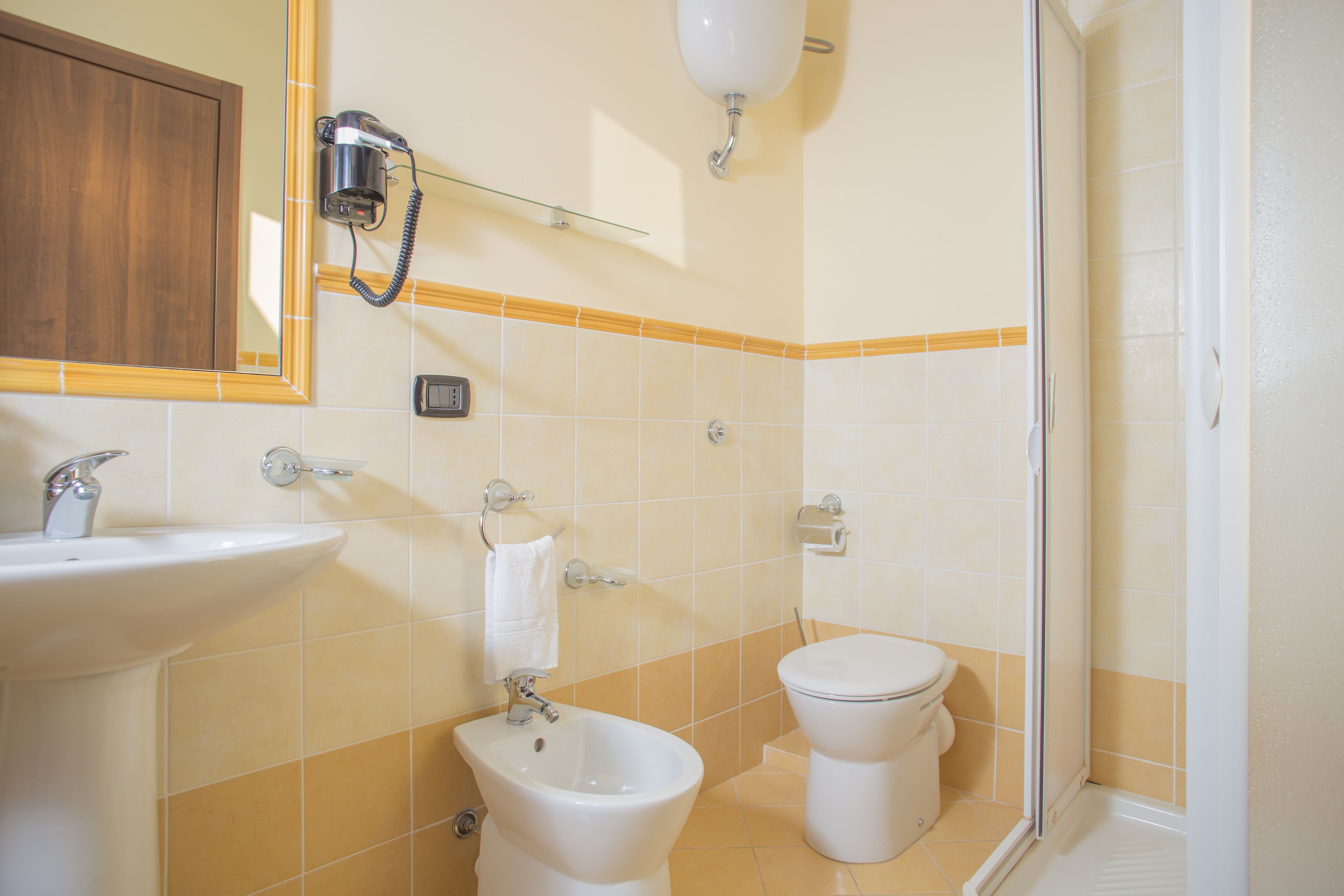 Un baño con lavamanos, bidé, inodoro y cabina de ducha de vidrio.