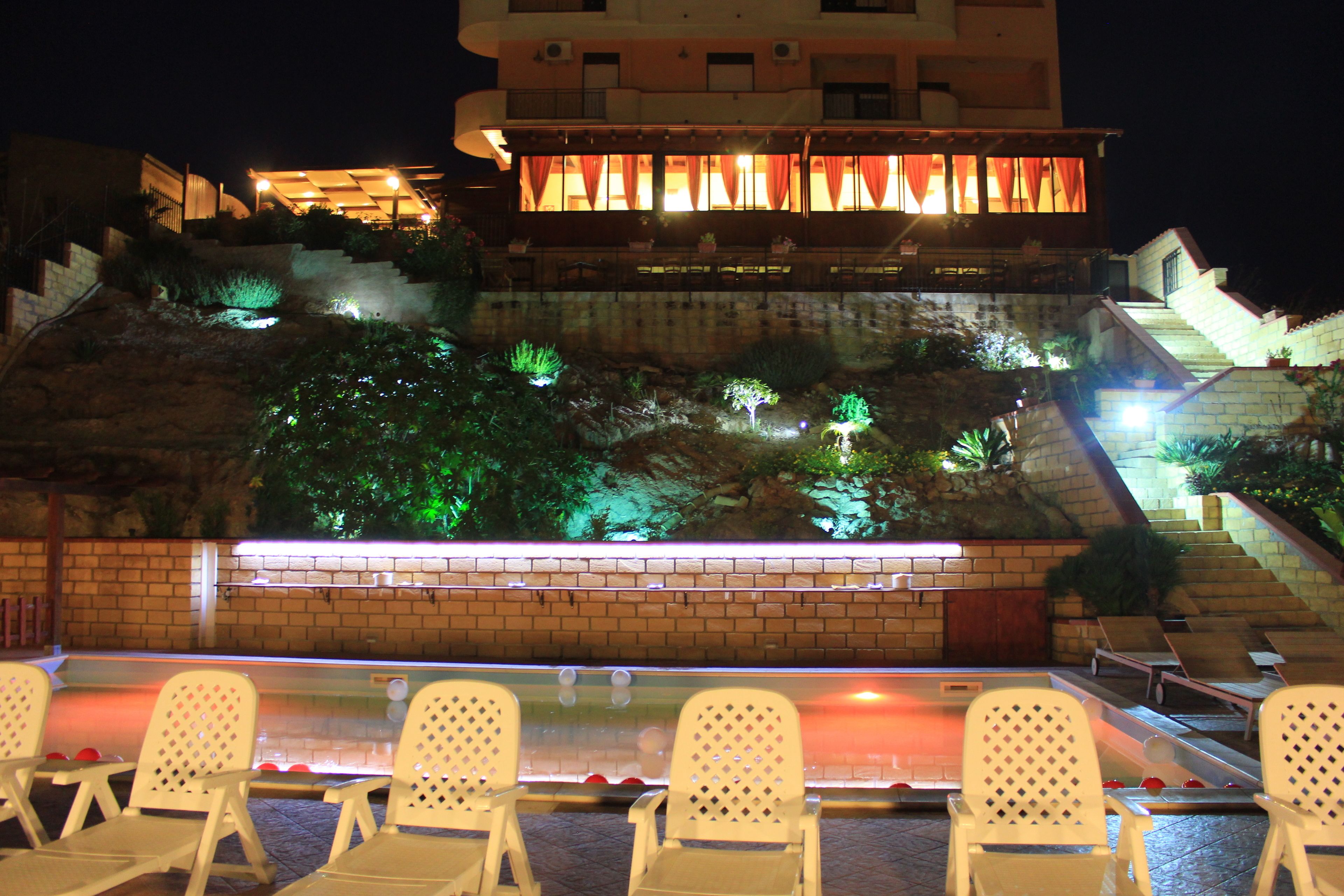 A pool area with white chairs and a brick wall.