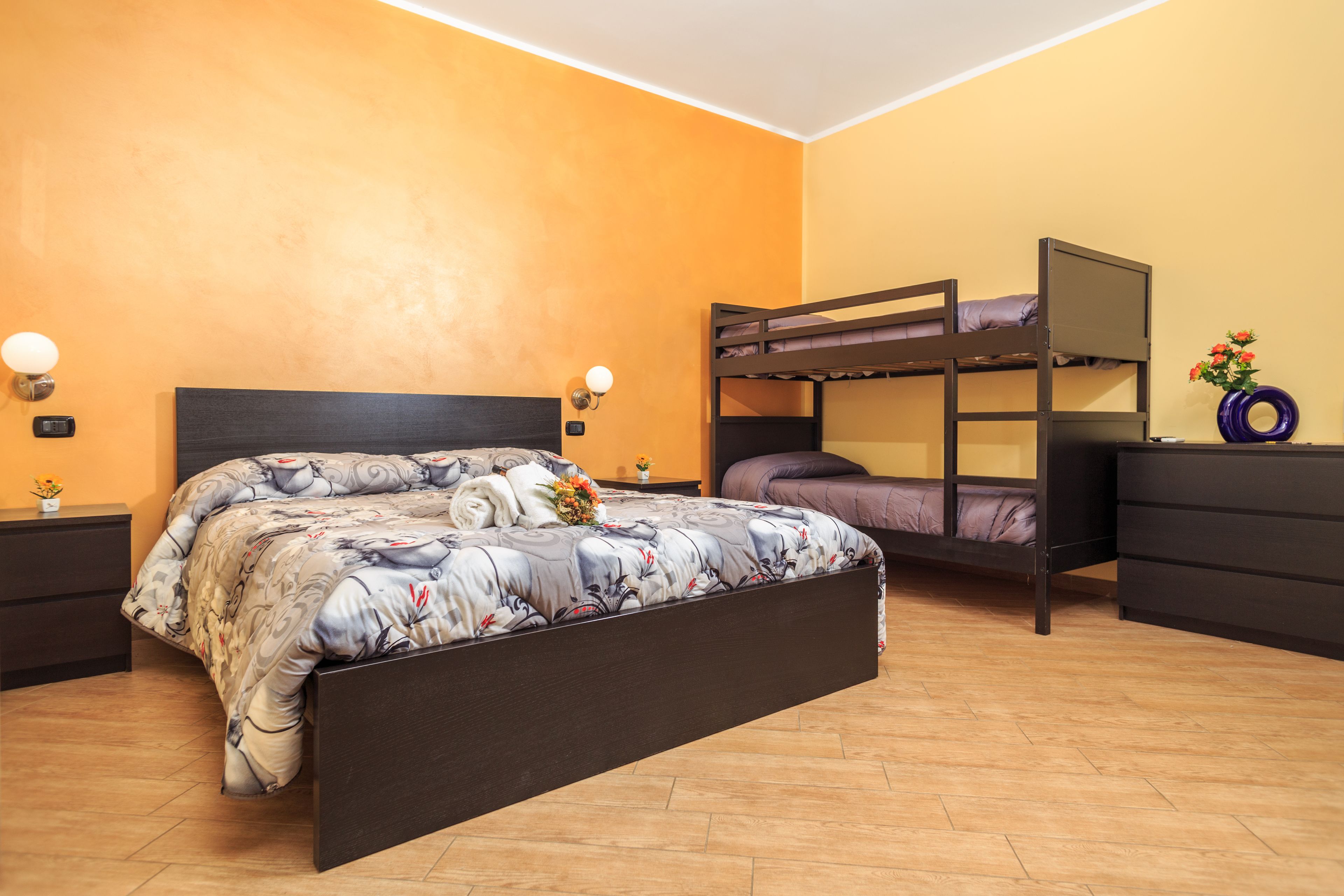 Een slaapkamer met een bed, een stapelbed, een kapstok en een nachtkastje.