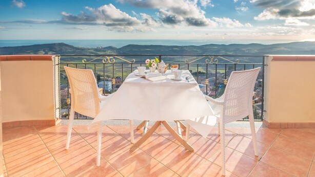 A terrace with a table set for two, overlooking a scenic landscape. - B&B Montemare (Agrigento)