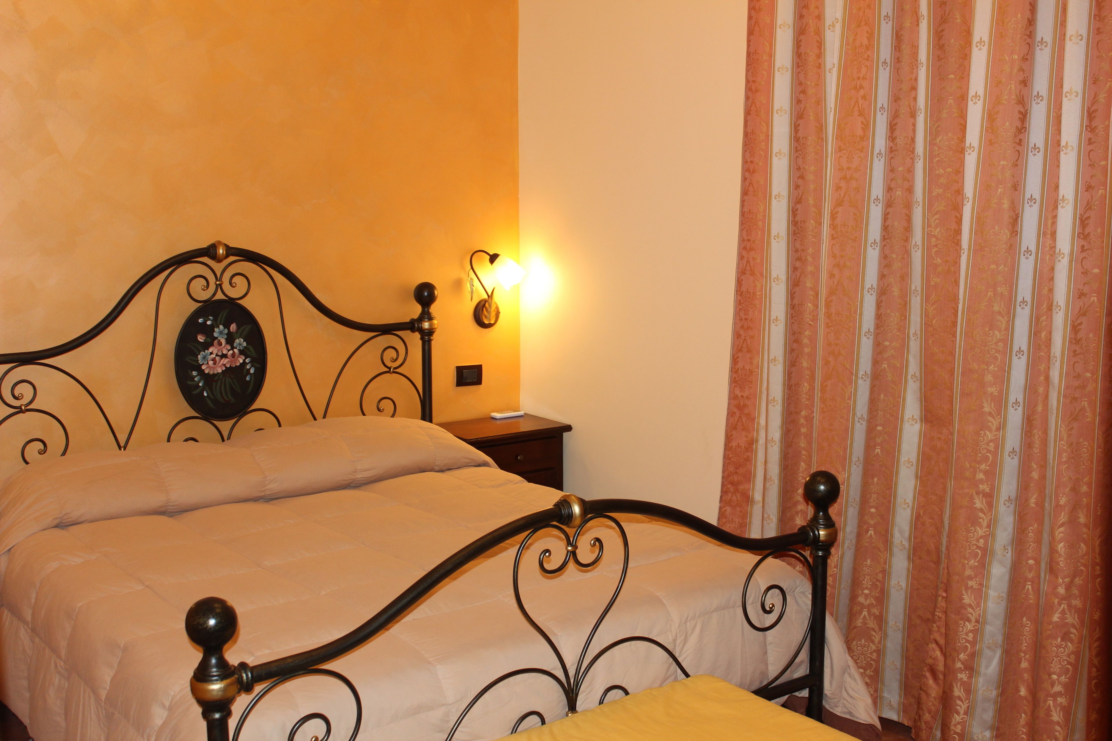 A bed with a headboard, a nightstand with a lamp, and a curtain.
