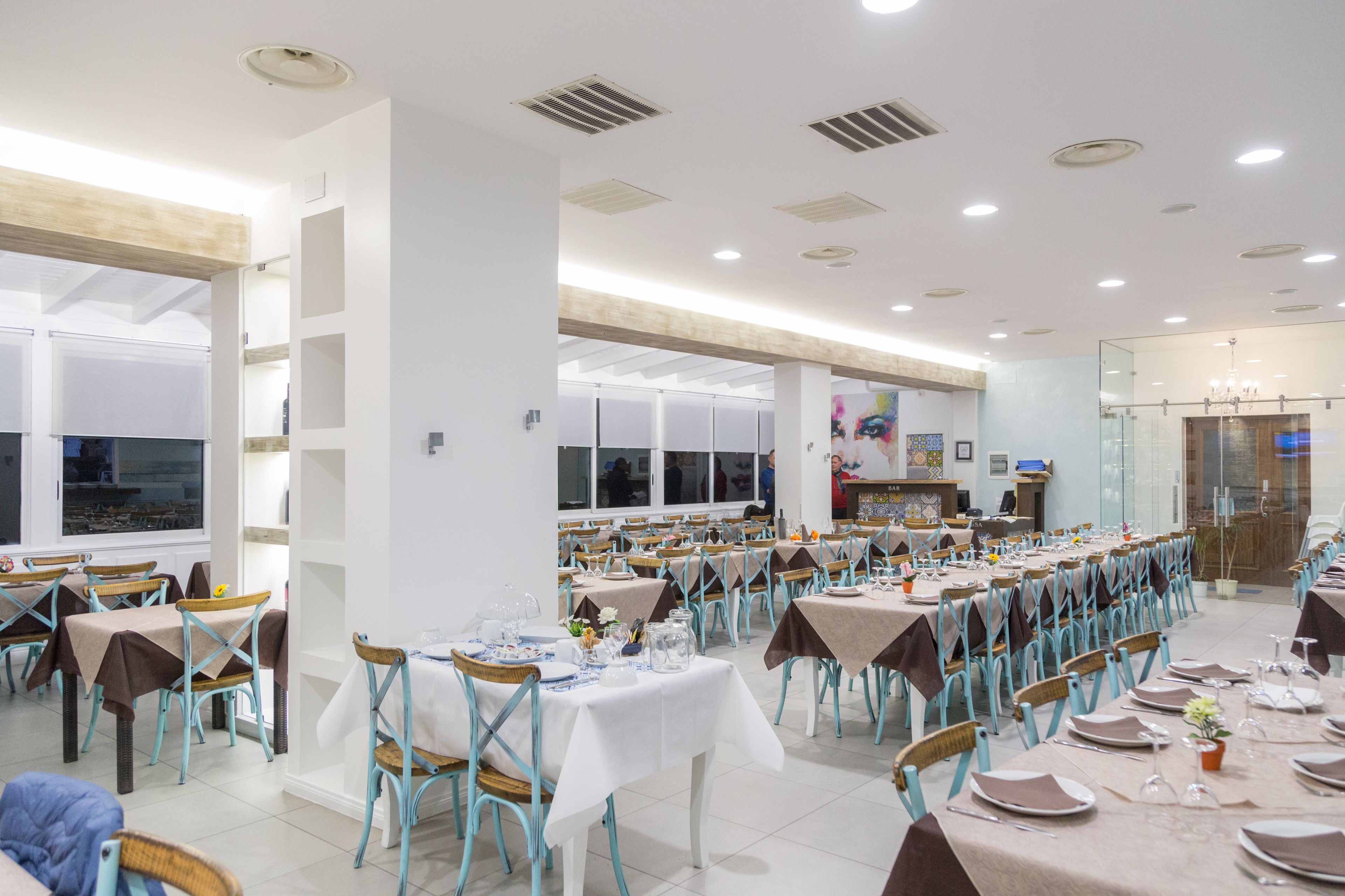 Un vaste espace dédié à la salle à manger, avec de nombreuses tables et chaises, de grandes fenêtres et un design moderne au niveau du plafond.