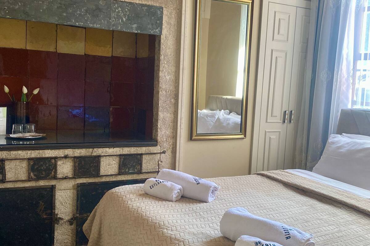 A hotel room with a bed, a mirror, a wardrobe, and a window with curtains.