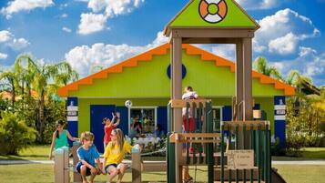 Un parque infantil con una estructura para escalar y una casita de juegos.