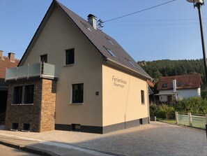 A two-story building with a beige facade, a sloped roof, and a sign reading "Ferienhaus Neumeyer".