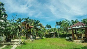 A spacious outdoor area with a well-maintained lawn, a gazebo, and a house with a red roof. - Anciano Beach House (Calatagan)