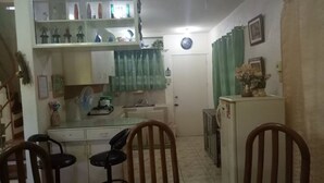 A compact kitchen with a dining area, a refrigerator, and a clock on the wall. - Anciano Beach House (Calatagan)