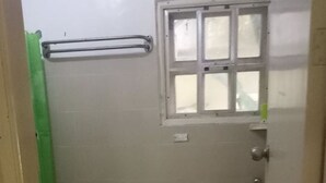 A small, basic bathroom with a toilet, sink, and window. - Anciano Beach House (Calatagan)