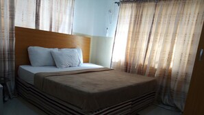 A hotel room with a bed, curtains, a bedside table, and a red rug. - Link Majestic B2 Suites and Hotel (Ibadan)