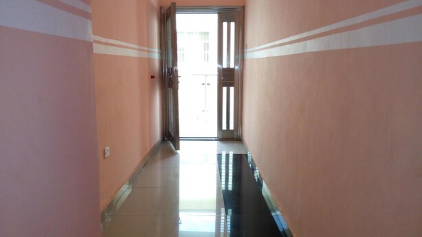 A corridor with a tiled floor and peach-colored walls with white stripes. - Link Majestic B2 Suites and Hotel (Ibadan)
