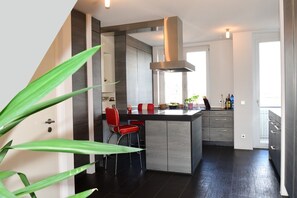 Een moderne keuken met een centraal eiland, rode barkrukken en een roestvrijstalen afzuigkap.
