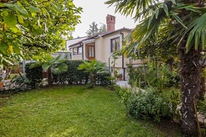 A house with a well-maintained garden, including a lawn and various plants.