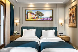 Ein Hotelzimmer mit einem großen Bett, zwei Nachttischen, einem Bild an der Wand und einem Fenster mit Vorhängen.