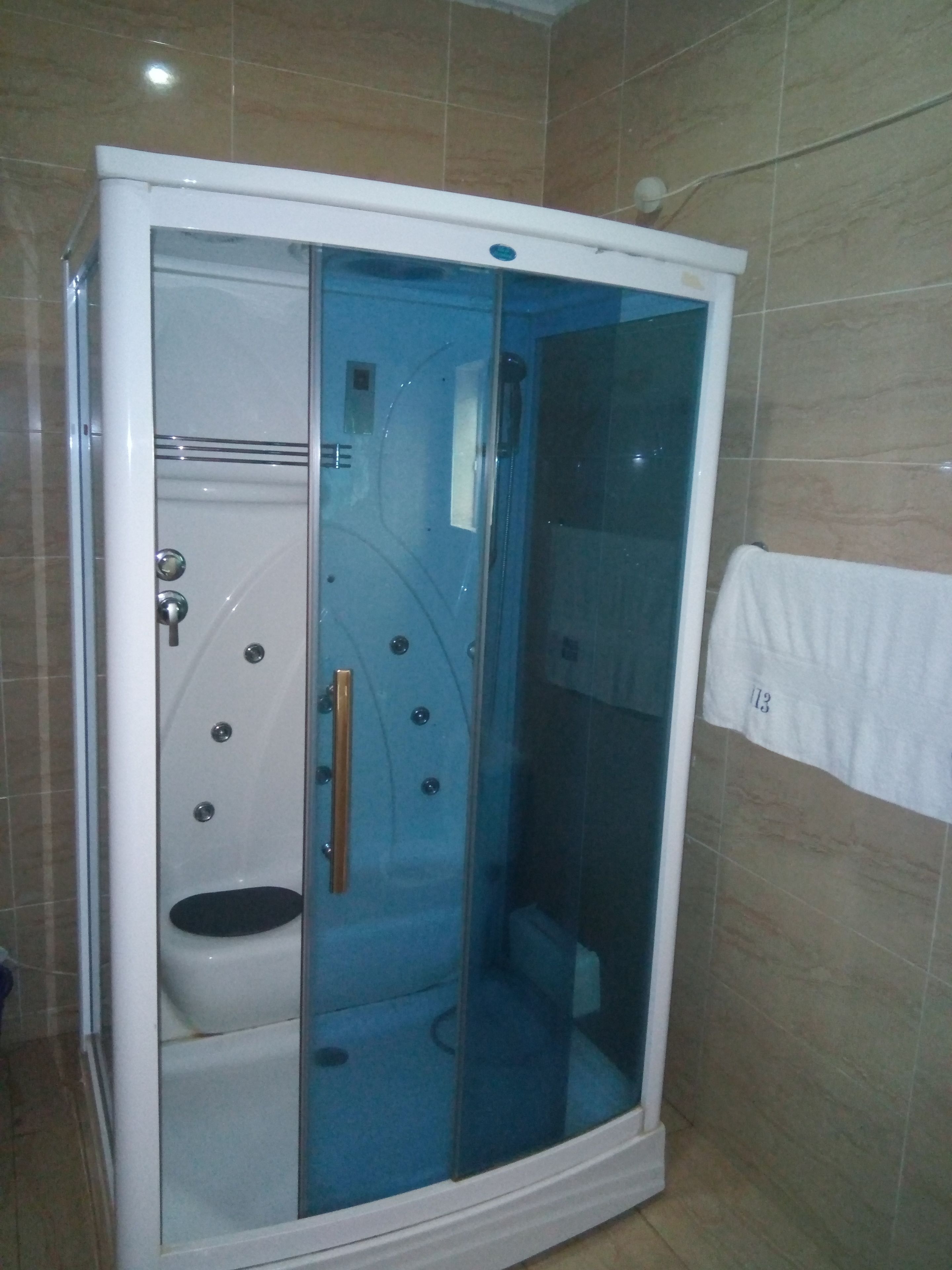 Box doccia a filo pavimento con porta in vetro, water e porta asciugamani.