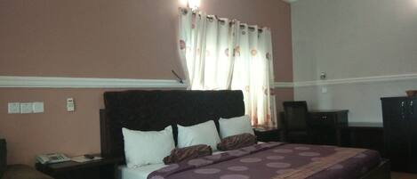 A bedroom with a bed, nightstands, a desk, and a chair.