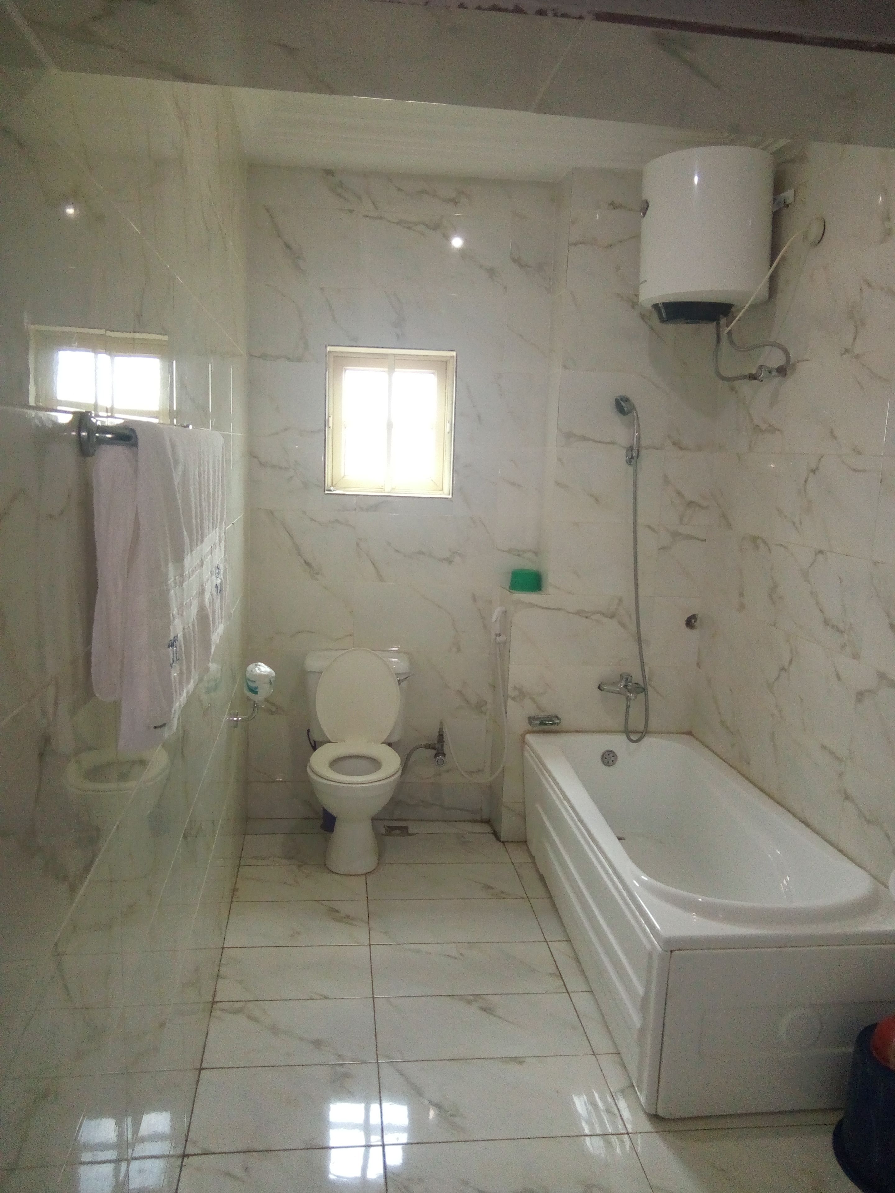A bathroom with a toilet, a bathtub, and a window.