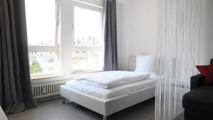 Een moderne hotelkamer met een groot bed, een zwarte bank en uitzicht op de stad door het raam.