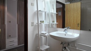 Een moderne badkamer met een witte wastafel, spiegel en planken voor toiletartikelen.
