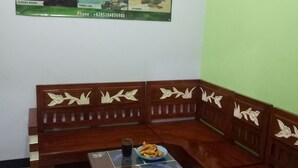 A room with a wooden bench and a table, a poster on the wall, and a glass of water on the table. - Kawah Ijen Guest House (Banyuwangi)