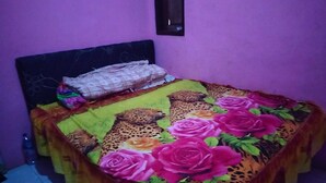 A small bed with a leopard print and rose pattern bedspread, a pillow, and a headboard against a purple wall. - Kawah Ijen Guest House (Banyuwangi)
