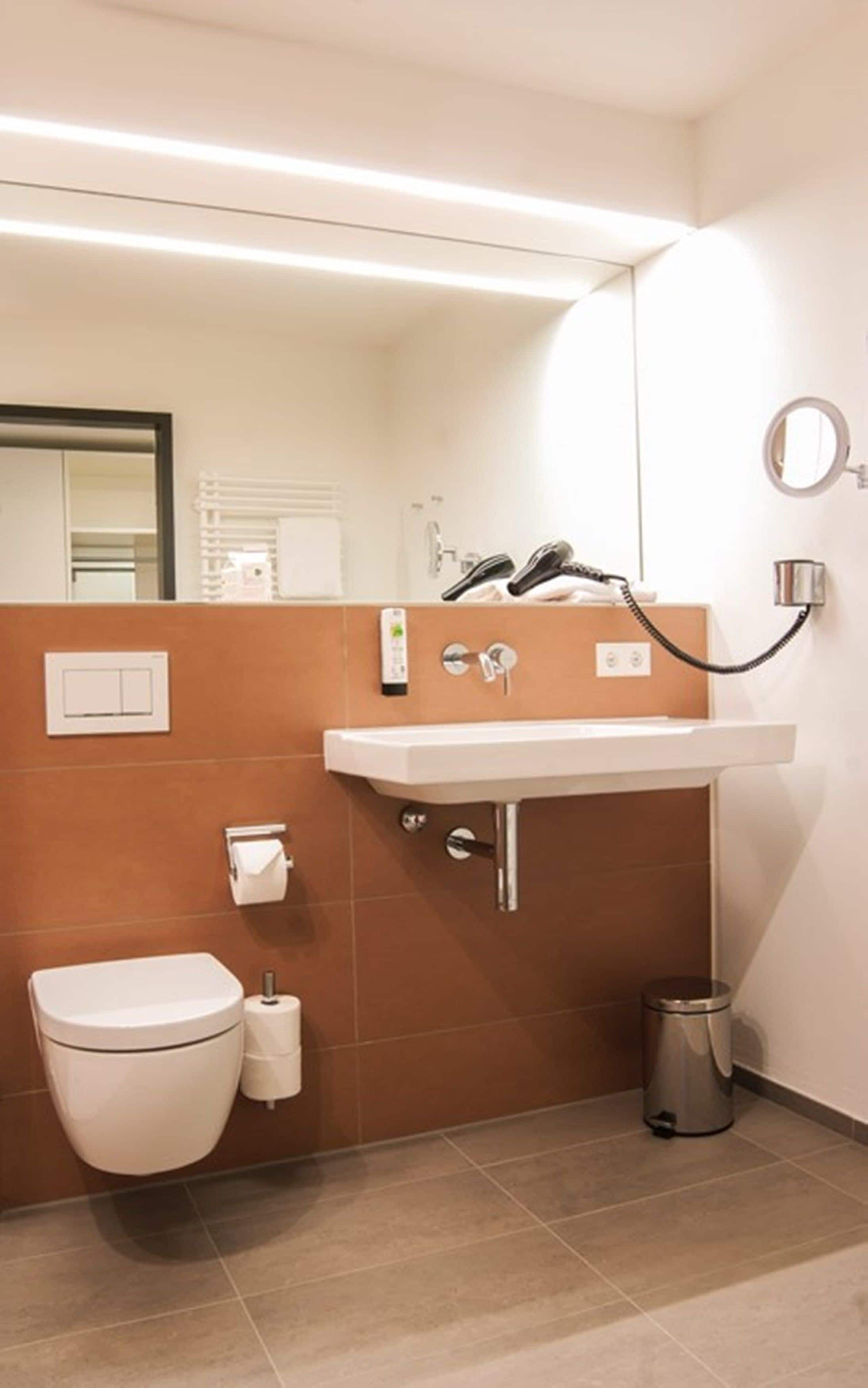 Een moderne badkamer met toilet, wastafel en spiegel.