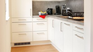 Una cocina moderna con armarios blancos, microondas y cafetera.