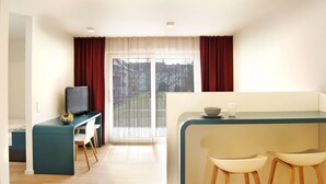 Una habitación moderna y bien iluminada con comedor, televisión y vistas a través de amplios ventanales.