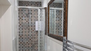 Un bagno con doccia, lavandino e specchio.