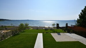 A view of a beach with a clear sky, a paved walkway, and a grassy area with umbrellas. - Acquarella Resort - Acquamarina Suite (TREVIGNANO ROMANO)