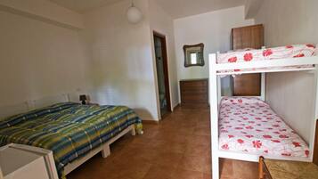 A dormitory room with two bunk beds, a small desk, and a mirror on the wall.