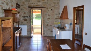 A rustic kitchen with stone walls, wooden cabinets, and a tiled floor. - Agriturismo Marano (Gubbio)