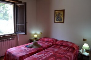A room with two beds, a window, a radiator, a wall-mounted picture, and two bedside lamps. - Agriturismo Marano (Gubbio)