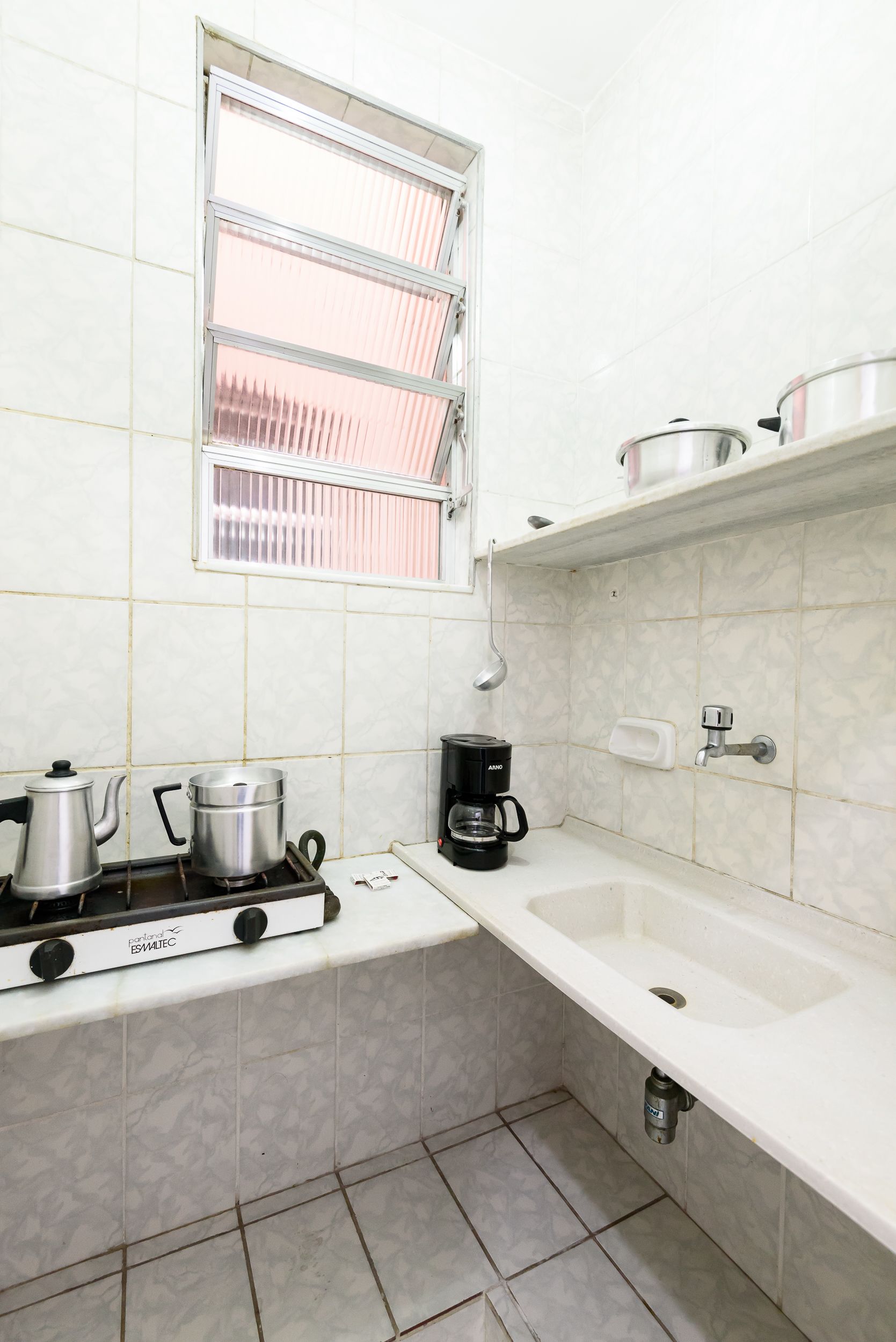 A kitchen with a gas stove, pots, a coffee maker, and a sink.