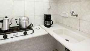 A kitchen with a gas stove, pots, a coffee maker, and a sink. - Omar do Rio - Apartamento A1202 (Rio de Janeiro)