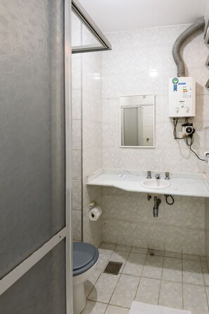 A bathroom with a toilet, sink, mirror, and a water heater.